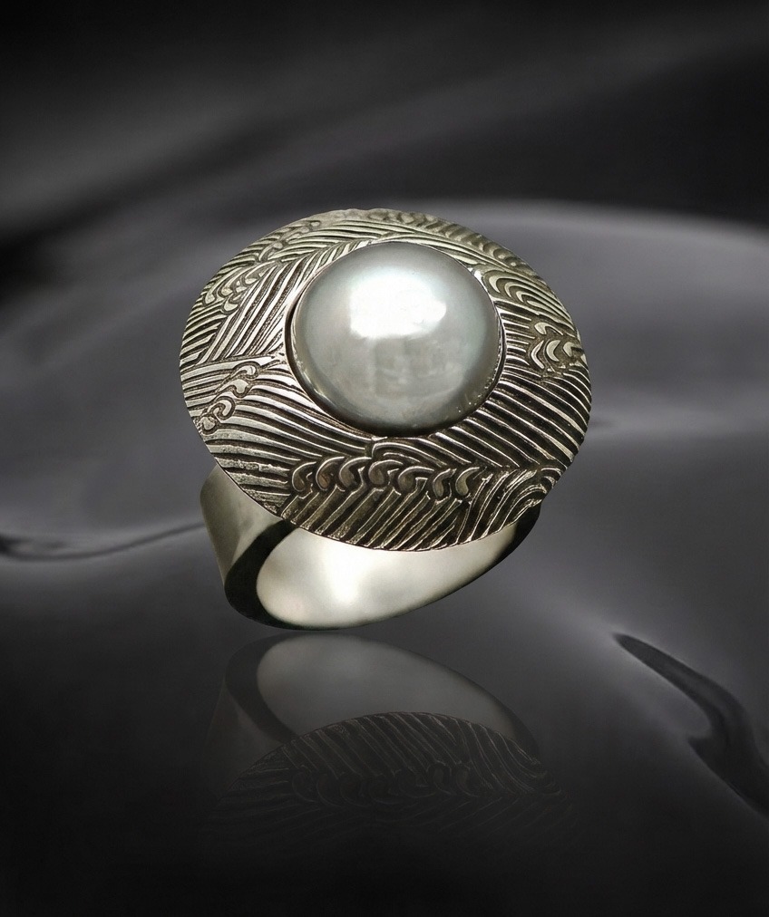 Silver ring featuring an intricate wave pattern and a prominent pearl centerpiece, highlighting its elegant craftsmanship and design.